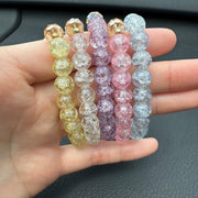 Handmade pink crackle beaded bracelet with white flower charm, gold crystals, and dangling bead, displayed in a gift box