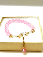 Handmade pink crackle beaded bracelet with white flower charm, gold crystals, and dangling bead, displayed in a gift box