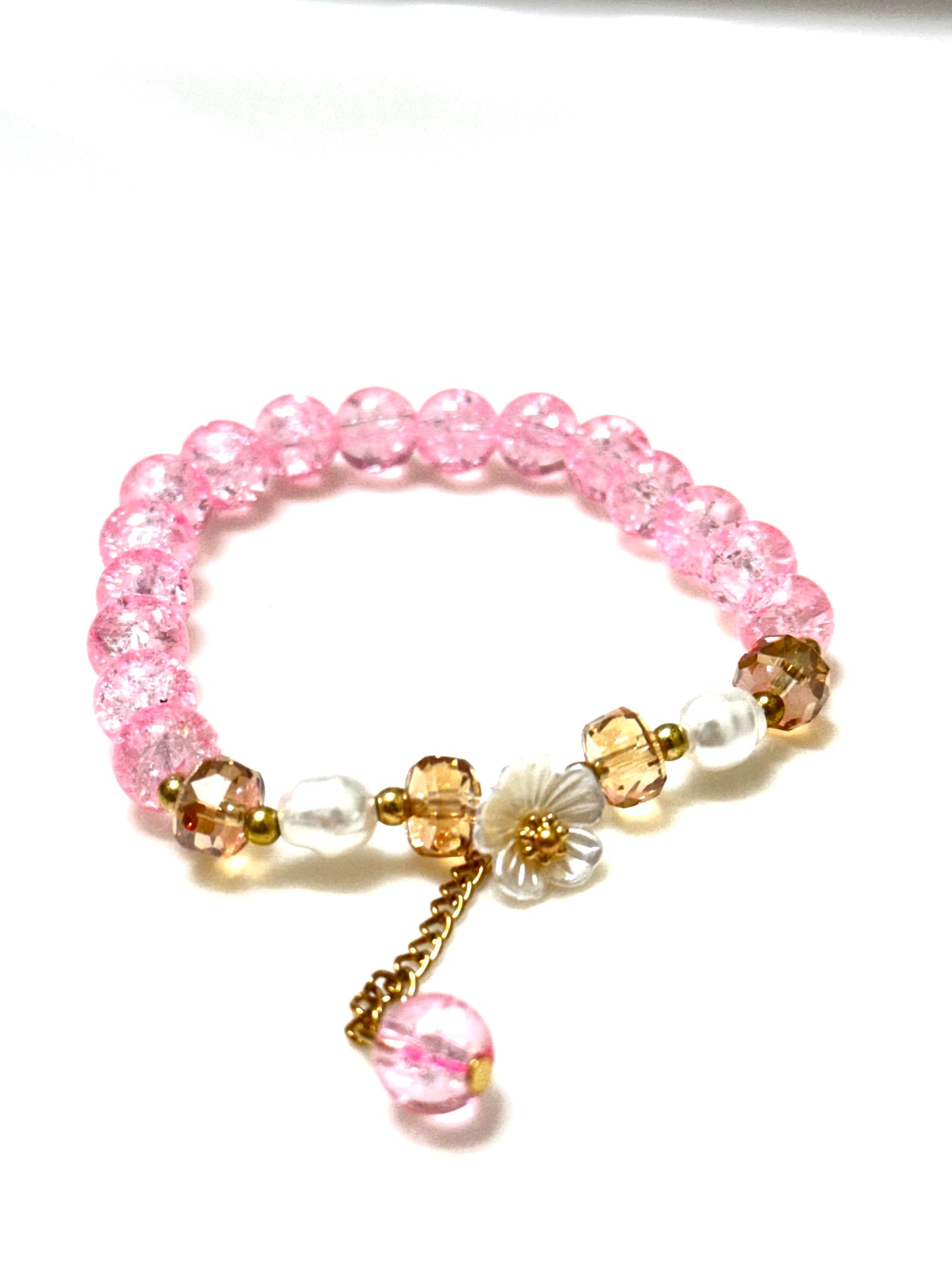 Handmade pink crackle beaded bracelet with white flower charm, gold crystals, and dangling bead, displayed in a gift box
